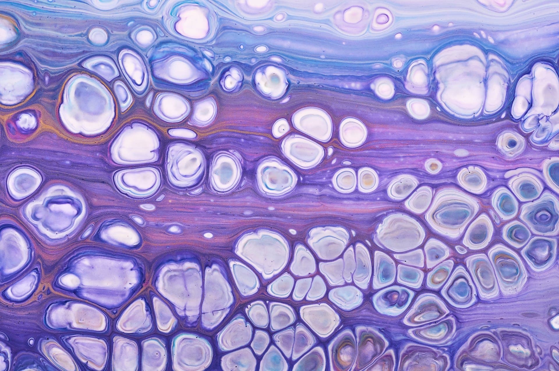 Abstract acrylic pour painting featuring flowing purple, lavender, and blue tones with cell-like bubble patterns evoking calm wellness.